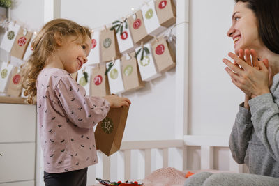 Mother with child opening christmas advent calendar tasks and gifts. toddler girl excited