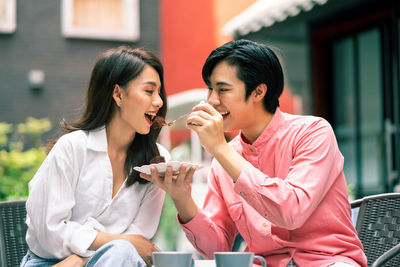 Smiling friends sitting on chair at home