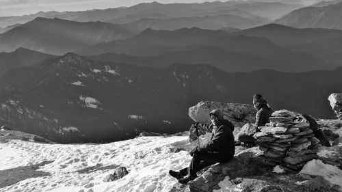 People sitting on rocks against mountains