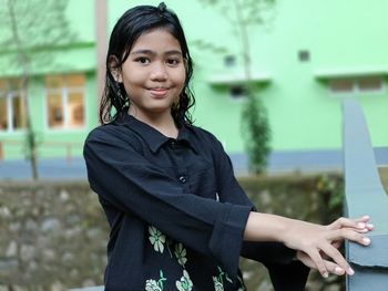 Portrait of young woman standing against building