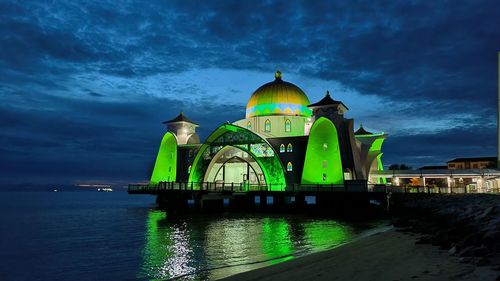 Lighthouse by sea against sky at night