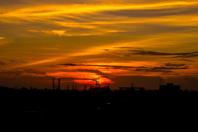 Silhouette of city against dramatic sky during sunset