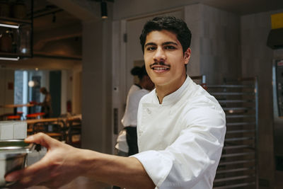 Portrait of happy male chef with mustache working in commercial kitchen