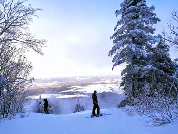 People on snow covered field against sky