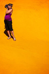 Full length of woman standing on yellow umbrella