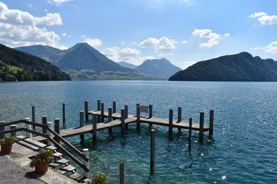 Wooden posts in lake against sky