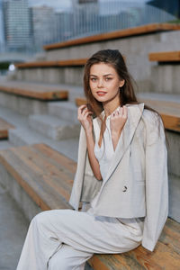 Portrait of young woman sitting on railing