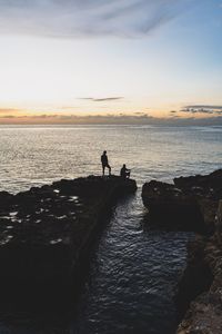 Silhouette people on beach against sky during sunset