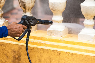 Man cleaning balustrade with water spray 