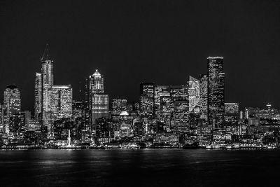 Illuminated buildings in city against sky at night