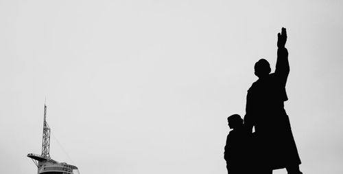 Low angle view of silhouette people against clear sky