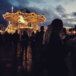 People in amusement park against sky at night