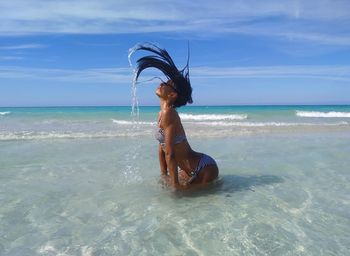 Young woman in bikini on beach against sky