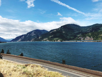 Scenic view of sea by mountains against sky