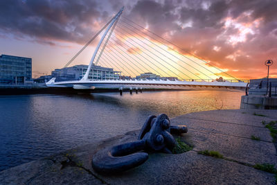 Bridge over river against cloudy sky during sunset