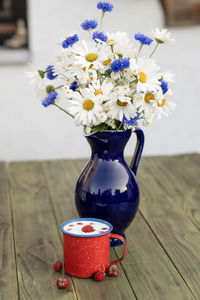 Fresh strawberry with cold milk in red mug on wild flowers background,childhood nostalgia healthy 