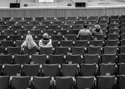 Rear view of people sitting on chairs at stadium