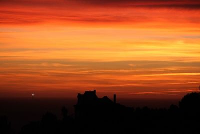 Silhouette buildings against orange sky
