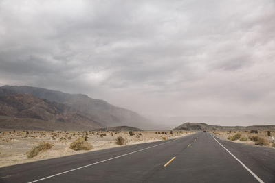 Road by mountains against sky