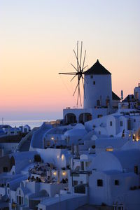 Traditional windmills in village at santorini against clear sky during sunset