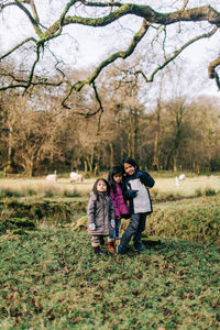 Friends standing on grass against trees