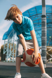 A beautiful boy in a sports uniform caught a basketball. a boy holds a ball in his hands 