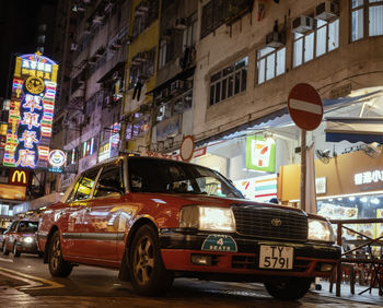 Cars on street against illuminated buildings in city at night
