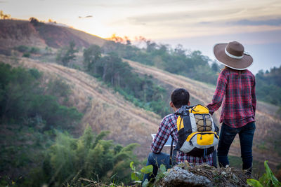 Rear view of father and son on landscape against sky