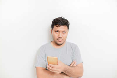 Portrait of young man using smart phone against white background