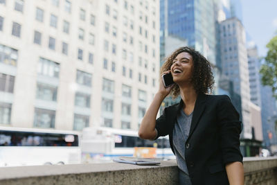 Smiling young man using mobile phone in city