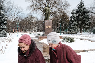 People on snow covered plants against trees during winter