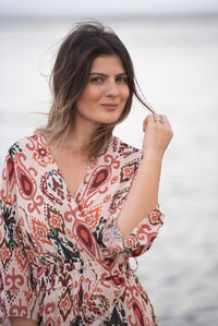 Portrait of beautiful woman standing against water