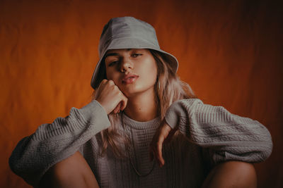 Portrait of young woman in hood clothing against wall