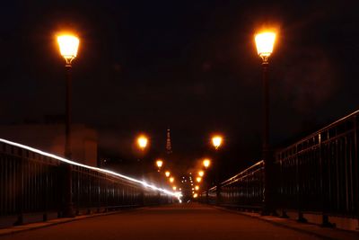 Illuminated street lights on bridge in city at night