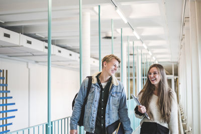 Smiling young woman using mobile phone in corridor