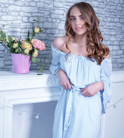 Portrait of a smiling young woman standing against wall