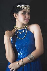 Close-up of smiling woman wearing jewelry against black background