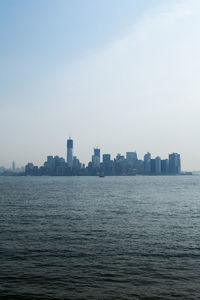 Sea by buildings in city against sky