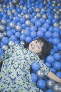 Portrait of smiling innocent girl lying down in ball pool