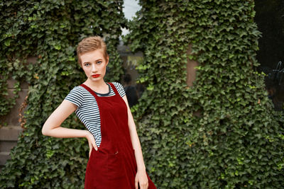 Portrait of young woman standing against plants