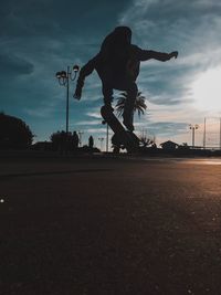 Man skateboarding on street against sky