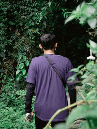 Rear view of man standing against trees