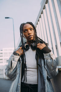 Young woman wearing denim jacket by fence