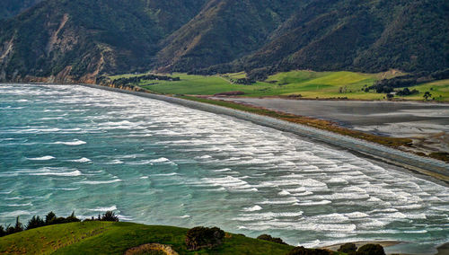 Scenic view of river by mountains against sky
