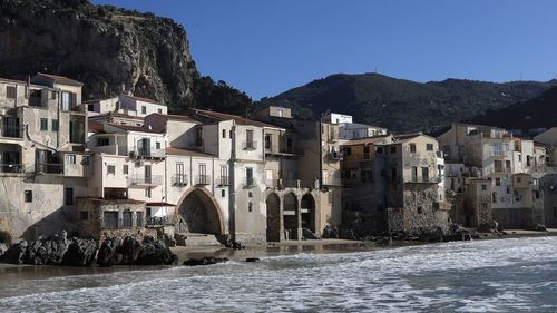 Houses by river in town against clear sky