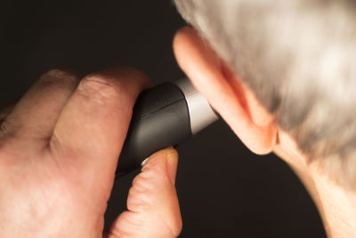 Close-up of man holding electric razor to ear