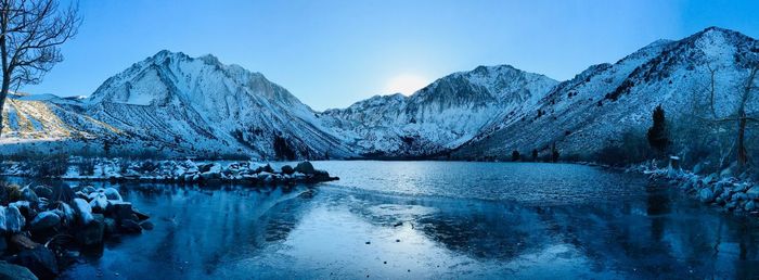 Scenic view of frozen lake by snowcapped mountains against sky