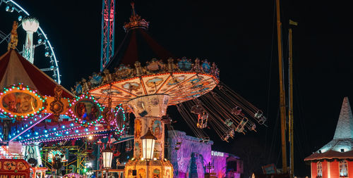 Low angle view of illuminated chain swing ride at night