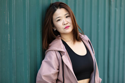 Portrait of young woman standing against yellow wall