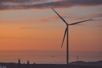 Silhouette of wind turbines on land during sunset